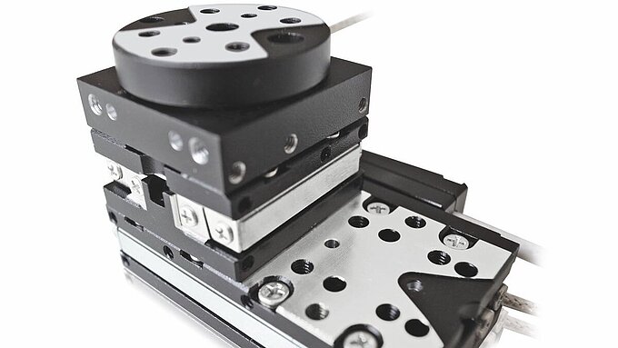 多軸積層型圧電ステージ。XYリニアステージベースが回転ステージとZ軸ステージを搭載し、精密位置決めのためのマルチステージアーキテクチャを示す